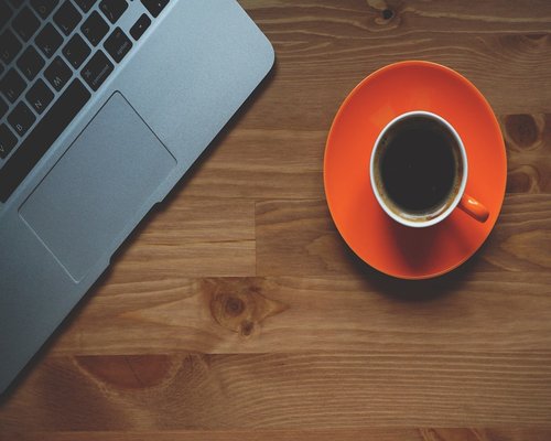 A cup of coffee next to closed laptop emphasizing a break time