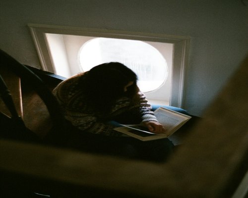 A person reading a book by a window with soft natural light