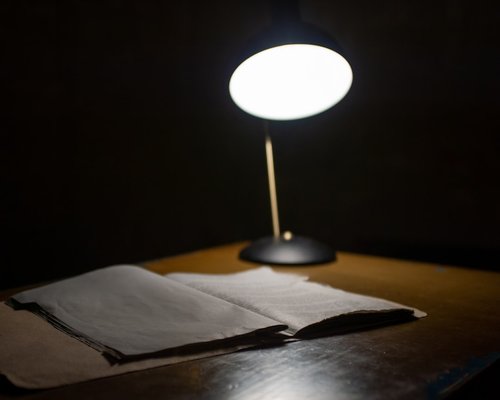 A desk lamp illuminating open pages of a notebook